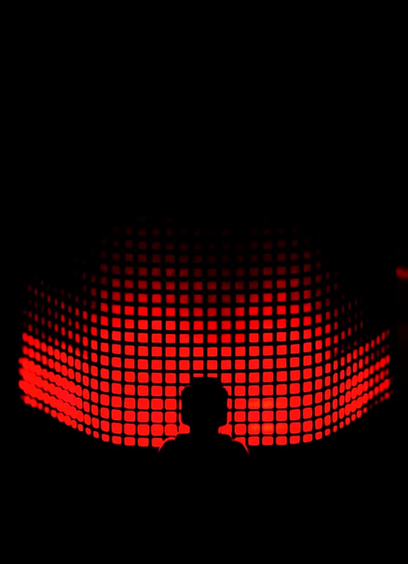 Silhouette of a person in front of a red LED display wall