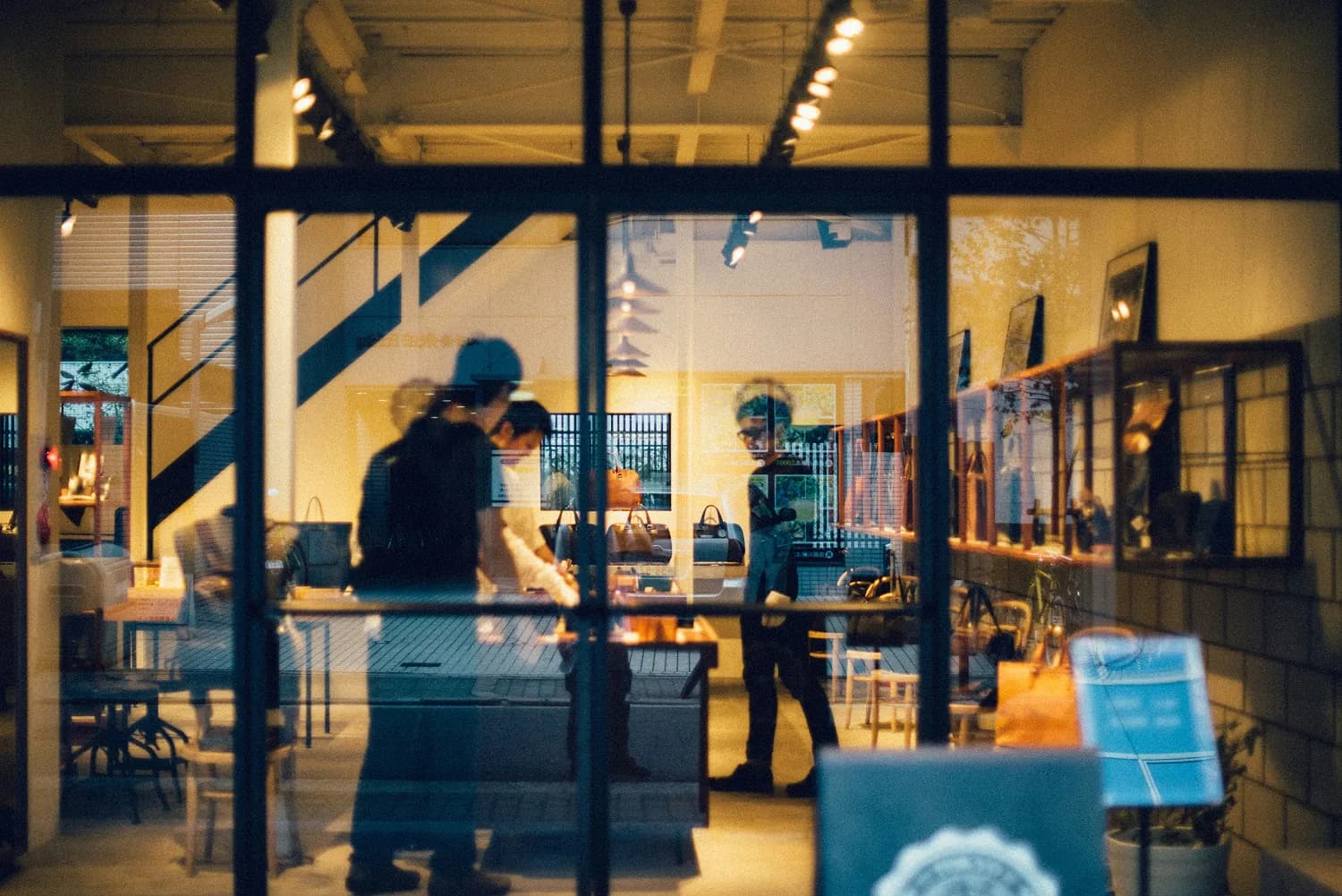 People browsing inside a warmly lit shop seen through a glass storefront