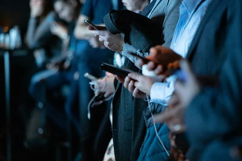 People in business attire using smartphones at an event