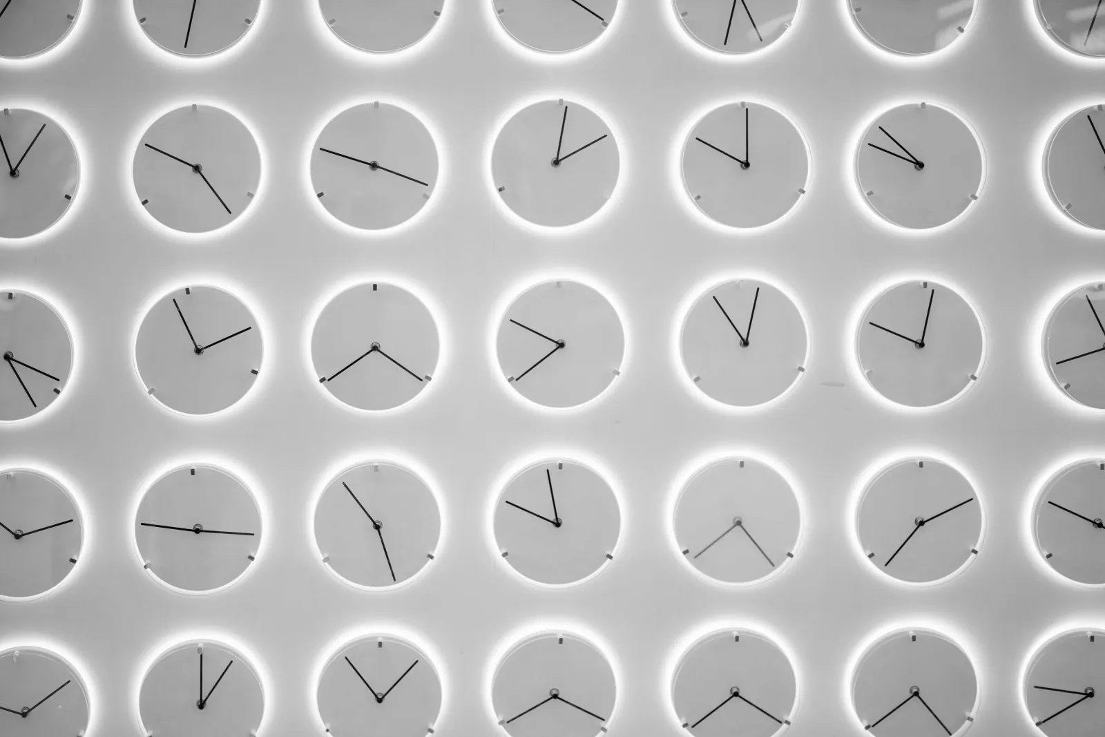 A wall of circular clocks showing different times in a grid pattern