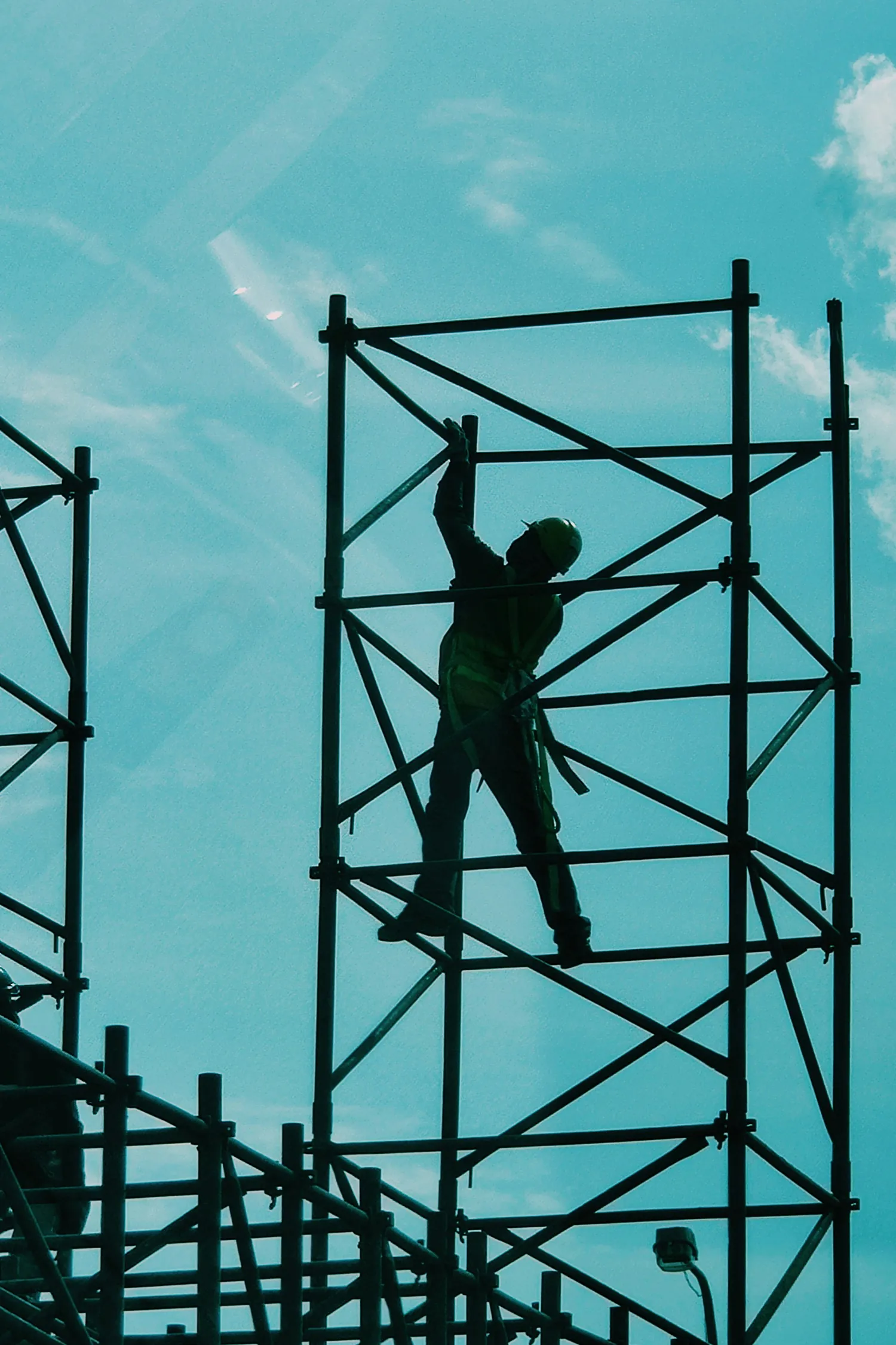 Construction worker on scaffolding against a blue sky