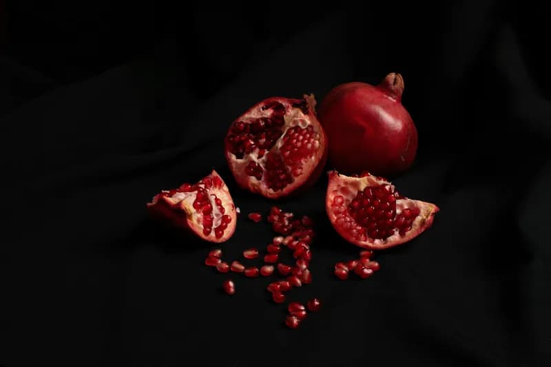 Pomegranate halves and seeds on a black background