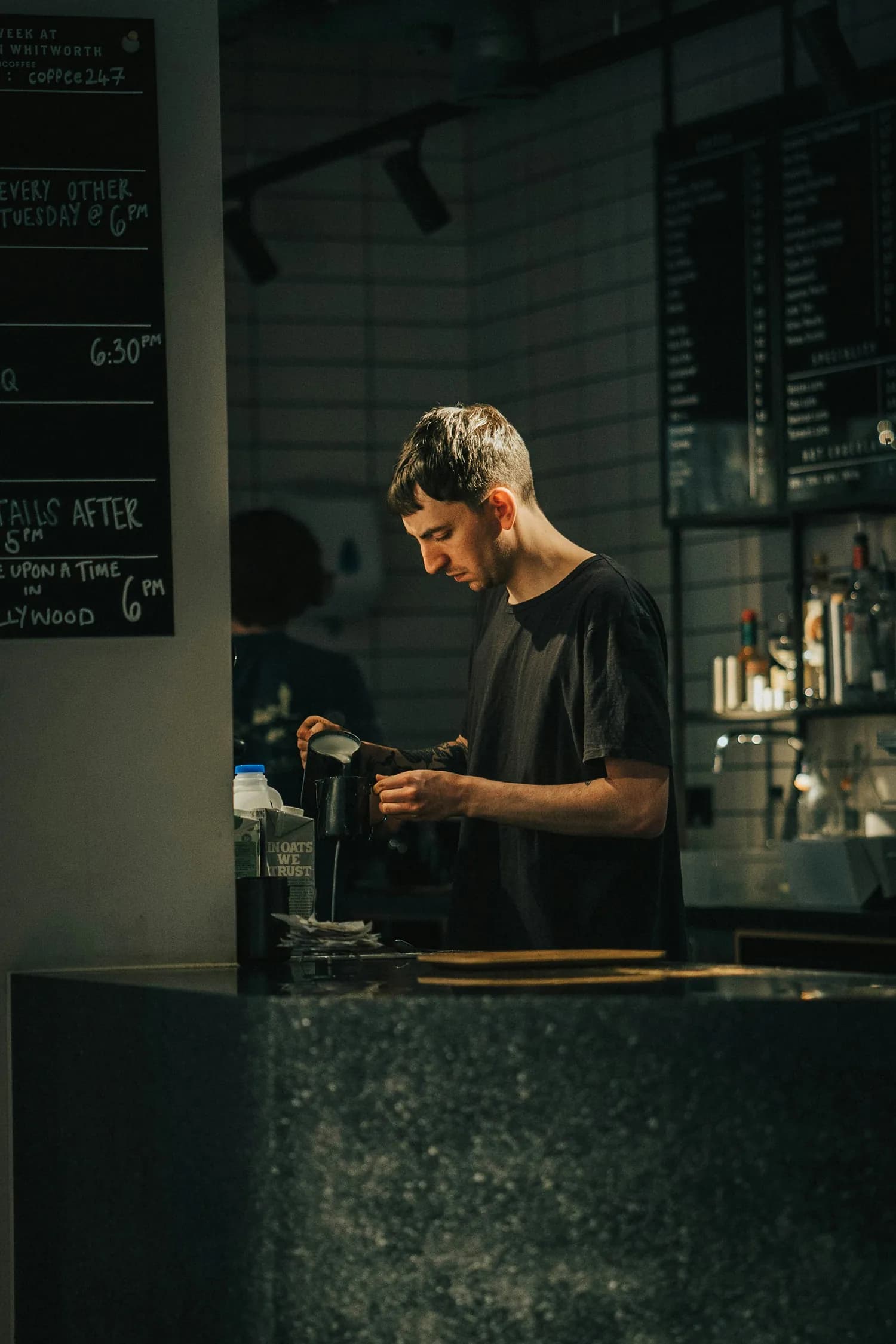 Barista pouring milk into a cup at a coffee shop counter