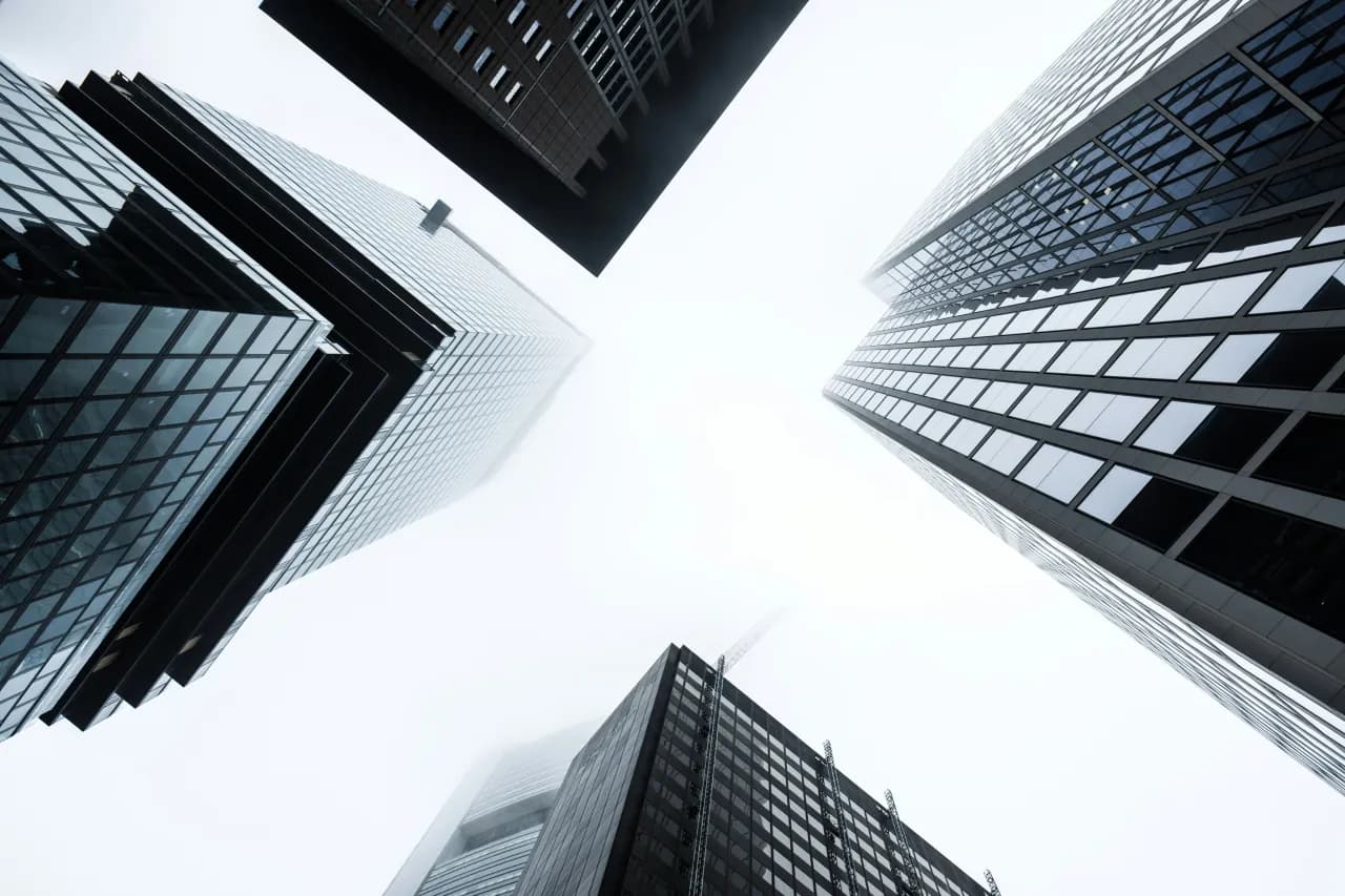 Looking up at tall glass office buildings against a bright sky