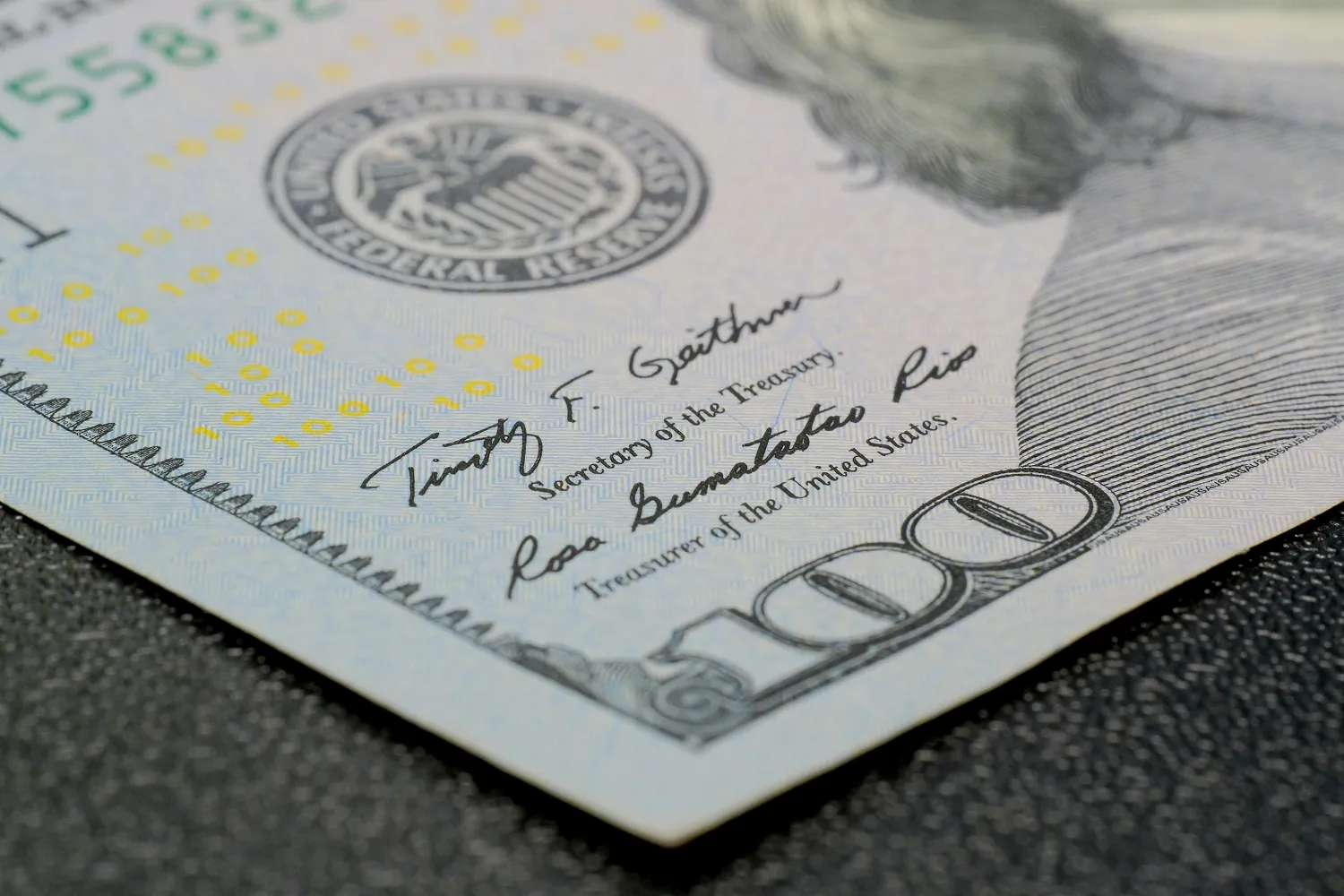 Close-up of a U.S. $100 bill with the Treasury seal and signatures visible