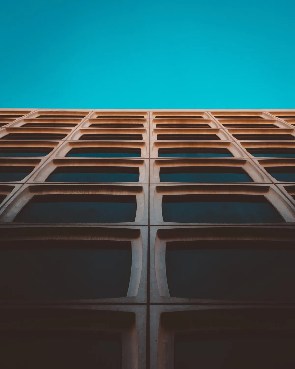 Low-angle view of a modern building facade against a clear blue sky