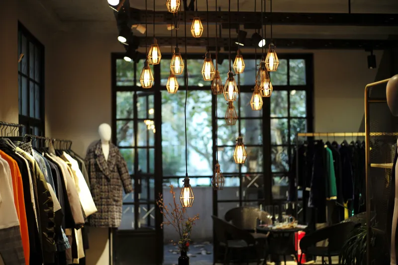 Clothing boutique interior with hanging pendant lights, racks of clothes, and a mannequin