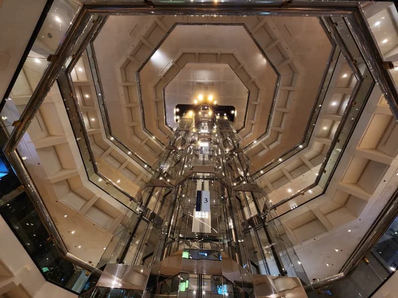 Interior view looking up an octagonal atrium with glass elevators and lights at Water Tower Place Shopping Mall