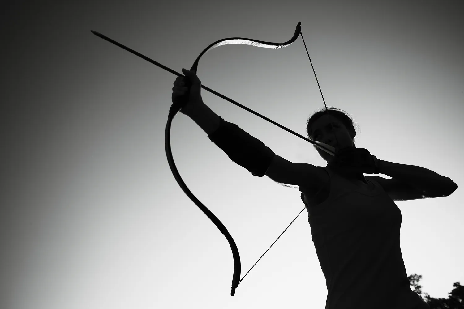 Silhouette of a person drawing a bow and arrow