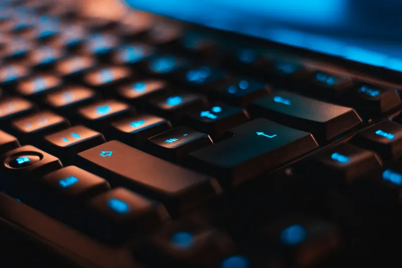 Close-up of a backlit computer keyboard with blue-lit keys