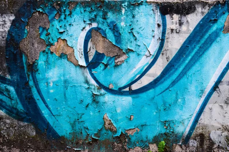 Peeling blue graffiti on a weathered wall