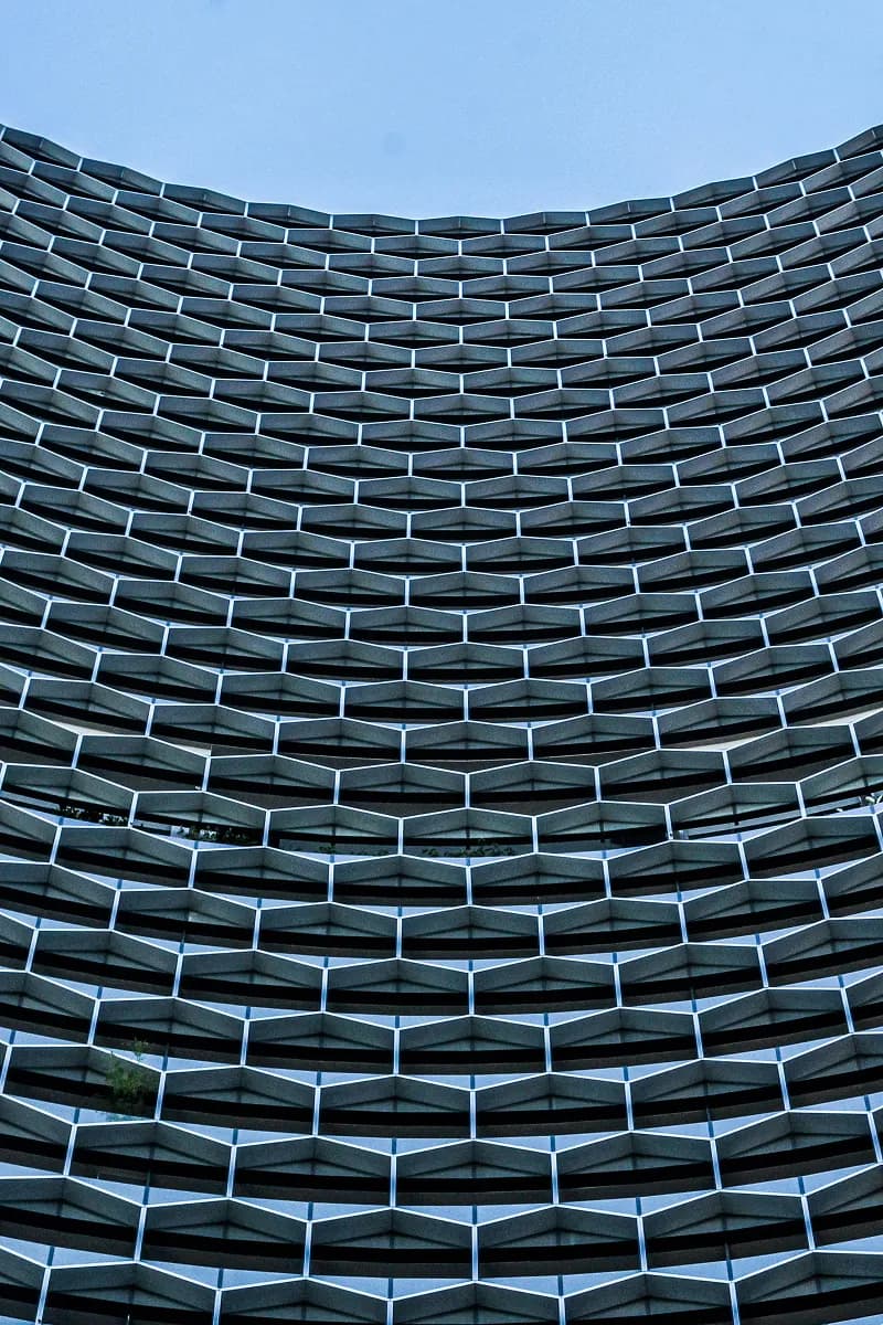Curved building facade with repeating geometric balconies against a blue sky