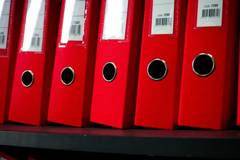 Red ring binders lined up on a shelf