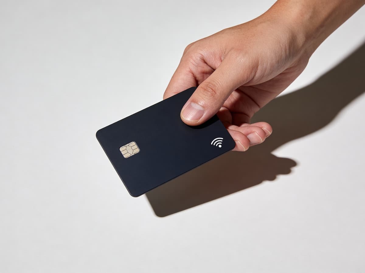 Hand holding black credit card isolated on white background